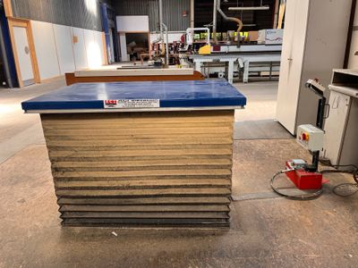 un plan de travail bleu posé dans un entrepôt, à côté d'un seau rouge