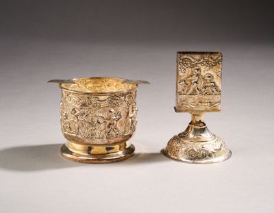 two silver cups with designs on them sitting next to each other