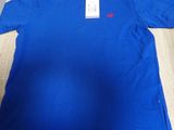 a blue t - shirt on a wooden table with a tag on it