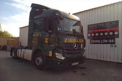 un gros camion vert garé devant un immeuble