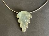 silver necklace with a green glass leaf pendant on a black surface