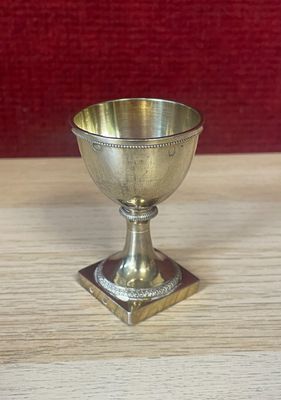 a silver cup on a wooden table with a red background