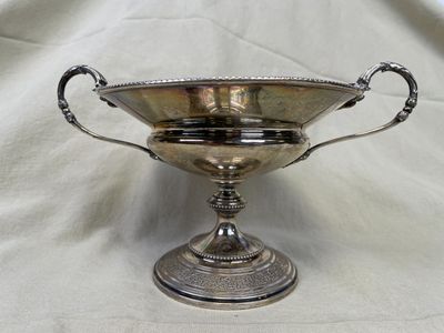 un bol ancien plaqué argent, muni d'anses, posé sur un tissu blanc