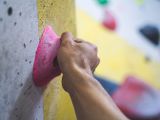 une personne qui fait de l'escalade sur un mur avec une prise rose