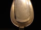 a silver spoon with a silver handle on a black surface