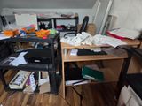 un bureau encombré sur lequel se trouvent un ordinateur portable et une imprimante
