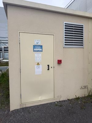 un petit bâtiment dont la porte est fermée et devant lequel se trouve une borne d'incendie