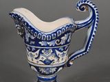 a blue and white pitcher with a handle on a gray surface