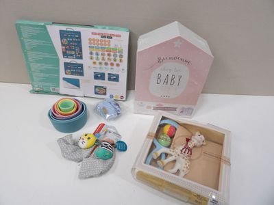 une boîte de jouets pour bébé posée sur une table, à côté d'un hochet pour bébé
