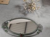 a mirror sitting on the floor next to a vase of flowers
