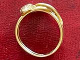 une image montrant un gros plan d'une bague en or posée sur une surface rouge