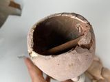 a person holding a broken vase with a wooden stick in it