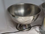 a silver bowl sitting next to a silver blender on a white table