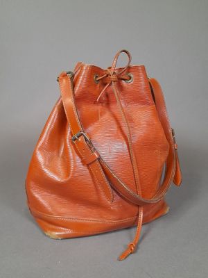 an orange leather bucket bag sitting on top of a gray surface
