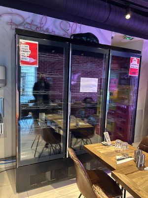 des tables et des chaises dans un restaurant, avec un réfrigérateur en arrière-plan