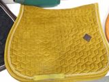 a yellow saddle pad on a table next to a pair of scissors