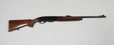 un fusil posé sur une table devant un fond blanc