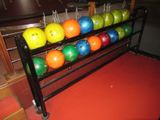 brightly colored bowling balls are lined up on a rack in a bowling alley