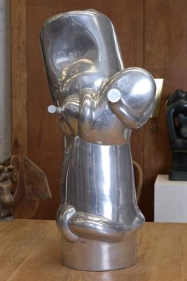 une sculpture métallique représentant une personne tenant une tasse posée sur une table