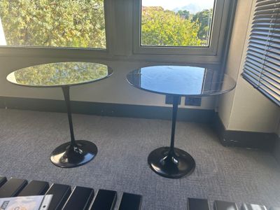 deux tables rondes en verre avec un piètement noir, placées devant une fenêtre
