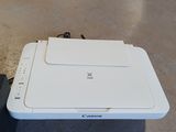 a white printer sitting on the floor next to a laptop
