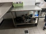 une femme debout dans une cuisine, avec des casseroles et des poêles posées sur le plan de travail