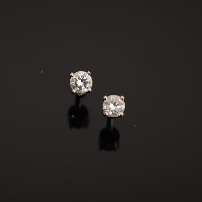 a pair of diamond earrings on a black surface