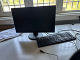 a computer monitor and keyboard on a desk in front of a window