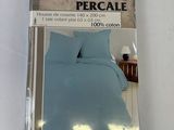 emballage d'un lit avec une couette bleue et un oreiller blanc