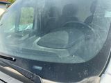 a dirty windshield of a car with a dog in the back seat