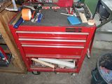 une boîte à outils rouge posée dans un garage, avec des outils dessus