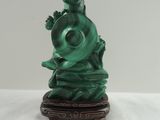 green jade statue of a woman holding a fish on a stand