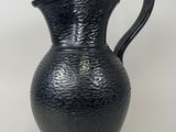 a black vase that is sitting on a white surface