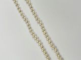 a close up of a necklace with pearls on a white surface