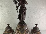 a statue of a woman holding a wand and a clock on a table