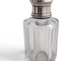 a glass bottle with a silver lid on a white surface