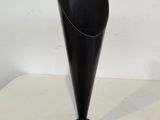 a black vase on a white table with a white background