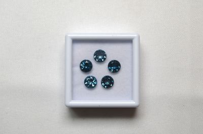 quatre diamants bleus dans une boîte blanche posée sur une surface blanche