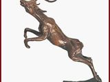 statue en bronze représentant un cerf bondissant sur un rocher, sur fond blanc