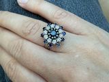 la main d'une femme portant une bague ornée d'un motif floral