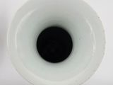 a white vase with a black spot in it