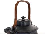 a black tea kettle with a wooden handle on a white surface