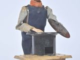 une figurine représentant un homme coiffé d'un chapeau, posée sur une boîte