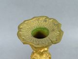 a gold vase with a green flower inside of it