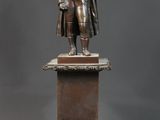 statue en bronze représentant un homme tenant un bébé dans ses bras, posée sur un socle