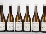 six bouteilles de vin sont alignées sur une table