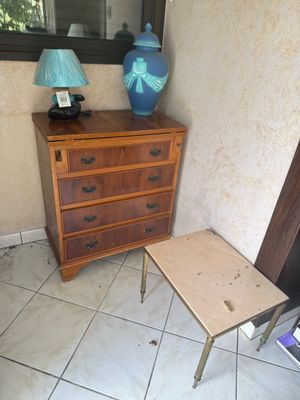 a small table with a lamp on it next to a chest of drawers