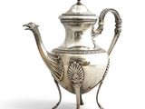 an antique silver tea pot with a peacock handle on a stand