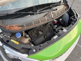 a green car with its hood open on the street