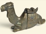 une statue en bronze représentant un chameau avec une selle sur le dos